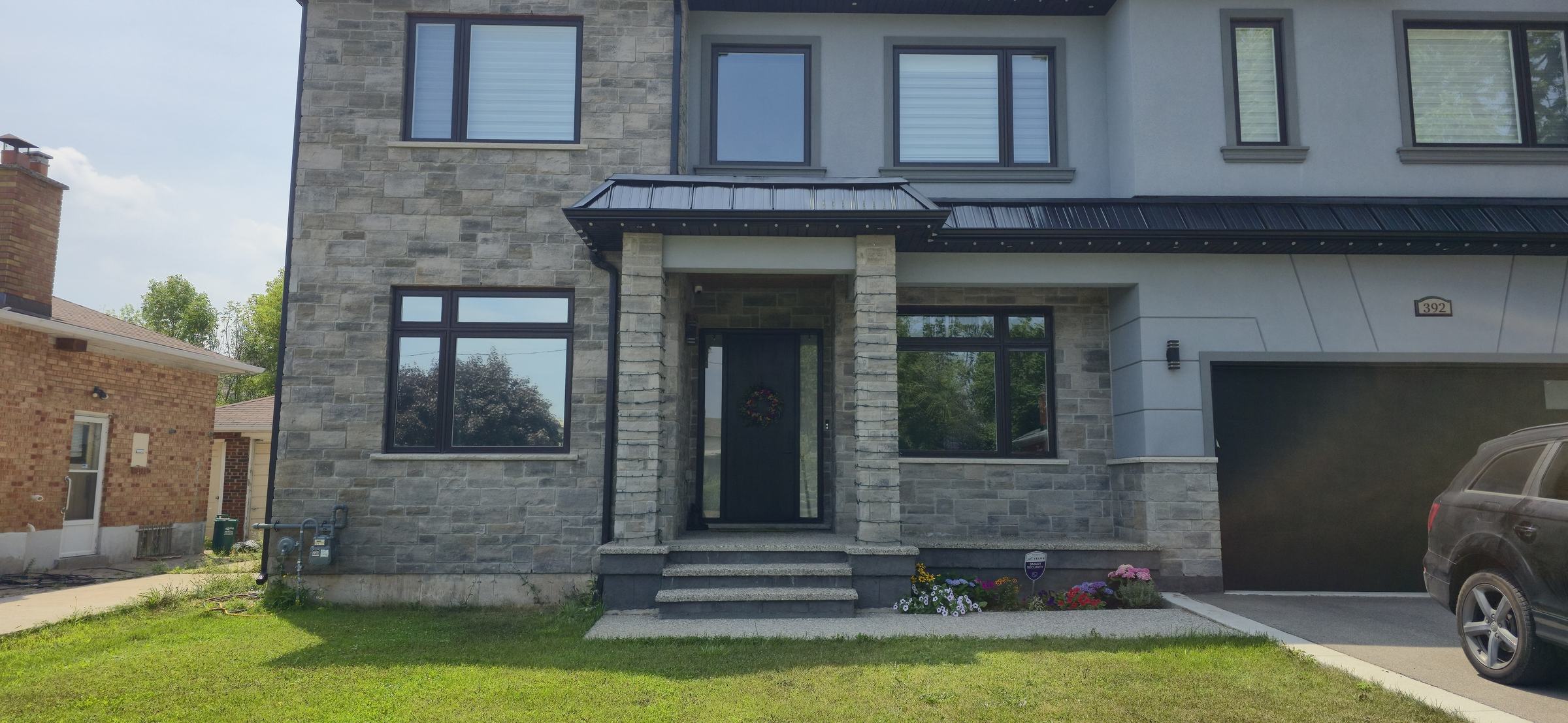 Two-storey stone home with dark solar window film installed on all windows
