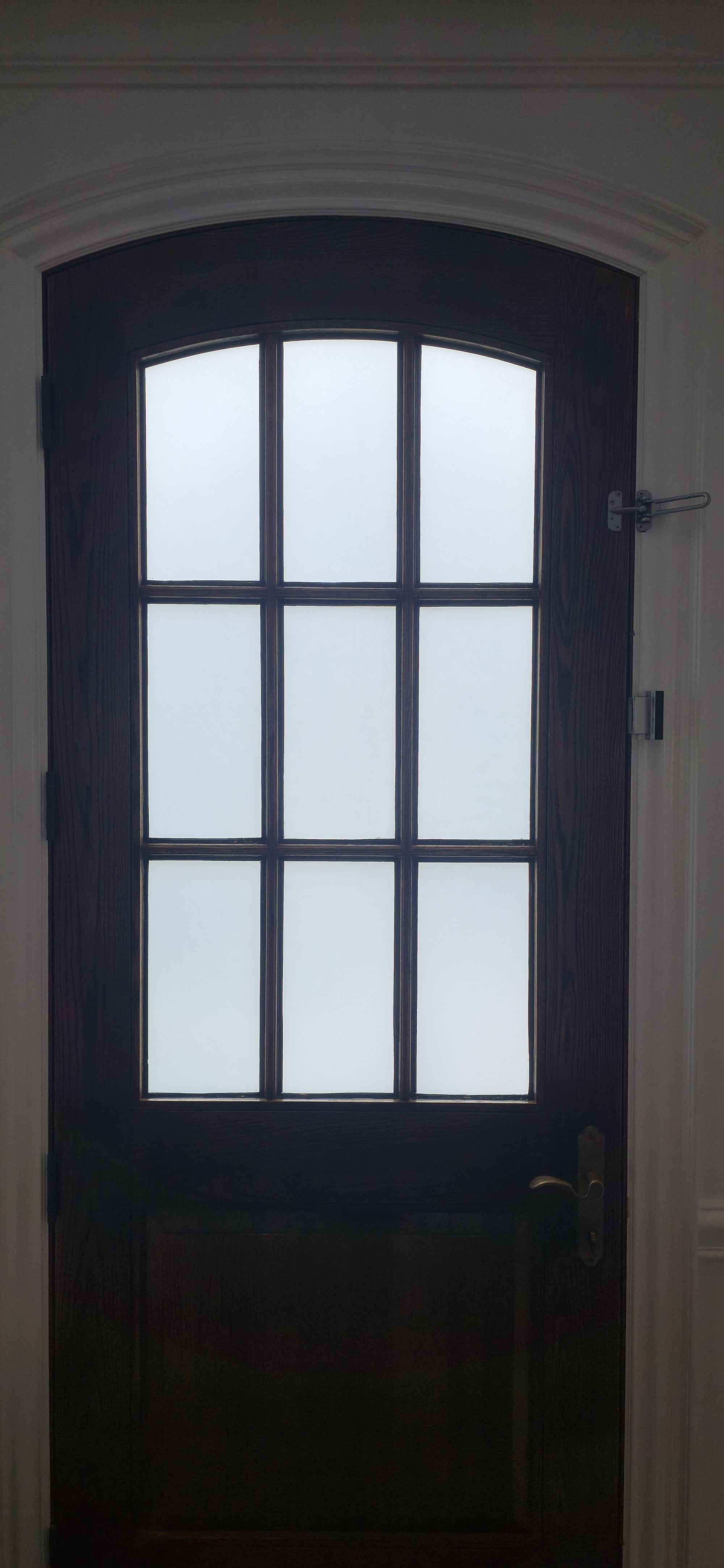 Arched dark wood door with backlit frosted security film inserts